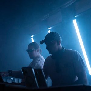 Zwei DJs am Mischpult bei blauem Licht